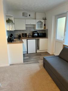 a kitchen with white cabinets and a couch in a room at Seaside Haven in Hunstanton