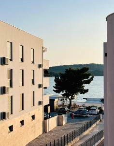 un edificio con coches aparcados en un aparcamiento junto al agua en Clouds Apartments Čiovo - 20 meters from Copacabana beach, en Trogir