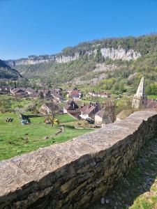 een stenen muur met een dorp op de achtergrond bij Gîte des trois petits oiseaux in Picarreau