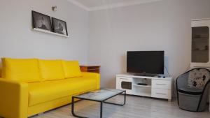 a living room with a yellow couch and a tv at Apartament w Centrum in Sandomierz