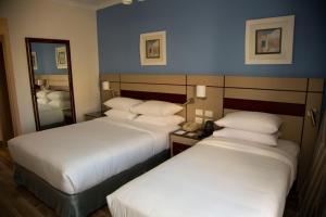 a hotel room with two beds and a mirror at Swiss Inn Resort Hurghada in Hurghada