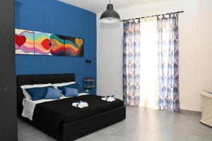 B&B Carlo V - House Hotel في كابوا: غرفة نوم بسرير اسود بجدار ازرق