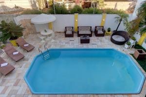 a large blue pool on a patio with chairs and tables at Casarão Serenitá in Aquiraz