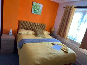 a bedroom with a bed with an orange wall at Quick Stop Night Stay - Gatwick in Crawley
