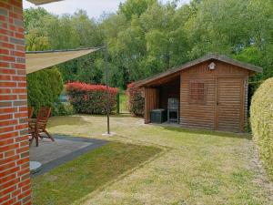 a wooden shed with a grill in a yard at Ferienhaus-Butterblume in Papenburg