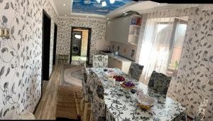 a dining room with a table and chairs and a kitchen at KF_Guest House-Madina in Shabdan +4 photos