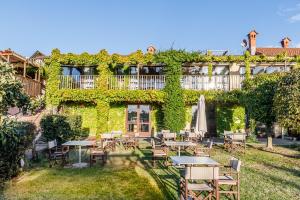 a building covered in ivy with tables and an umbrella at Foresteria Settevie in Treiso