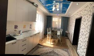 a kitchen with white cabinets and a blue ceiling at KF_Guest House-Madina in Shabdan