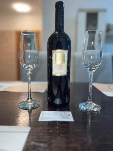 a bottle of wine and two wine glasses on a table at Apartman Nada de lux in Vrnjačka Banja
