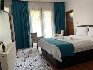 1 dormitorio con 1 cama grande y cortinas azules en Uzungol Soylu Hotel, en Uzungöl