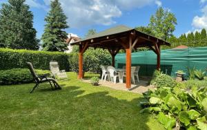 a wooden gazebo with a table and chairs in a yard at Heilmann Ház in Harkány