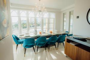 a dining room table with blue chairs and a chandelier at Ocean House, Tenby in Tenby