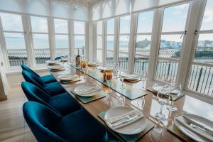 a dining room with a table and chairs and windows at Ocean House, Tenby in Tenby