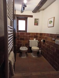 a bathroom with a toilet and a brick wall at Casa El Inglés in Mora de Rubielos