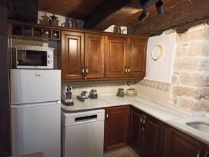 a kitchen with a white refrigerator and wooden cabinets at Casa El Inglés in Mora de Rubielos