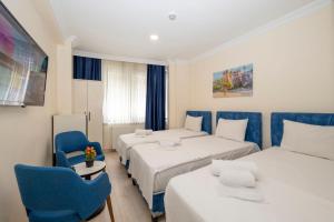 een hotelkamer met 2 bedden en een blauwe stoel bij Hotel Grand İstanbul in Istanbul