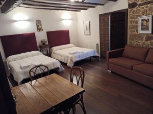 a room with two beds and a table and a couch at Casa El Inglés in Mora de Rubielos