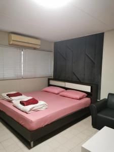 - une chambre dotée d'un lit avec des draps roses et une chaise dans l'établissement Popular Condo by Jintana, à Pak Kret