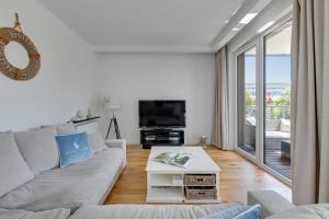 a white living room with a couch and a tv at Grand Apartments - Apartament Tre Mare - By the sea in Gdańsk