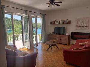 ein Wohnzimmer mit Sofas, einem TV und einem Balkon in der Unterkunft Captain Ante's House in Dragove