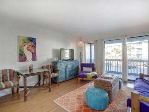 a living room with a tv and a table and chairs at Beach and Racquet in Tybee Island