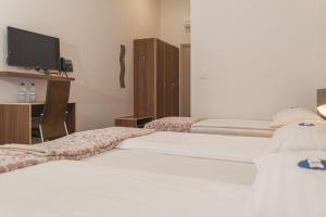 two beds in a hotel room with a tv at Hotel Lavender - Oleander Resort in Strunjan
