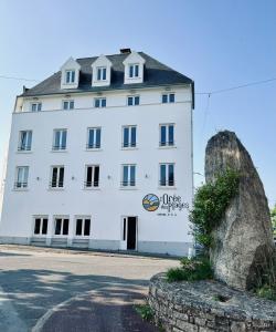 a white building with a sign on the side of it at Hôtel L'Orée des plages in Clohars-Carnoët