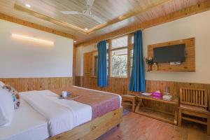 a bedroom with a bed and a flat screen tv at SaffronStays Kesar Villa, Manali - beautiful villa amidst an apple orchard - All clear roads in Manāli