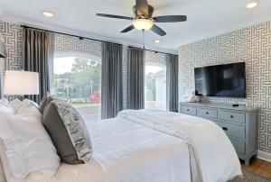 um quarto com uma cama branca e uma televisão de ecrã plano em El Rey Collection 2 em Tybee Island