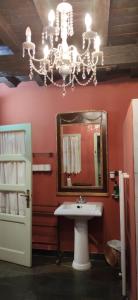 La salle de bains est pourvue d'un lavabo, d'un miroir et d'un lustre. dans l'établissement Casa rural con piscina privada, à Casar de Palomero