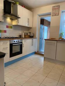 a kitchen with white cabinets and a stove top oven at Specious 2 x double bedroom flat in London E18 in London