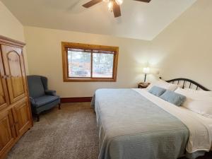 a bedroom with a bed and a chair and a window at Columbine B Cabin Suite in Woodland Park