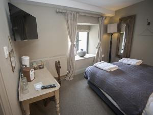 a bedroom with a bed and a table and a window at Timbrell's Yard in Bradford on Avon