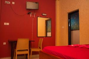 Schlafzimmer mit roten Wänden sowie einem Tisch und Stühlen in der Unterkunft Hotel Janara in Kurunegala