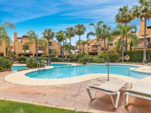 einen Pool mit Palmen und Gebäuden in der Unterkunft Casa las Salinas in Marbella