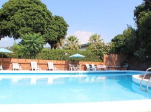 a large swimming pool with chairs and umbrellas at Villa Louise by Holiday World in Aci Castello