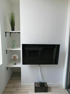 TV de pantalla plana colgada en una pared blanca en Jungle Zen Beau T2 avec jardin Gare 100m, en Tonneins