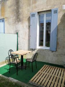 una mesa y sillas en un patio con ventana en Jungle Zen Beau T2 avec jardin Gare 100m, en Tonneins