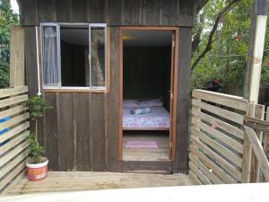 een houten buitenhuis met een bed in de deur bij Quarto do Madruga in Ilha do Mel