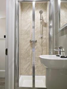 a shower with a glass door next to a sink at Hyde Park Superior Apartments in London