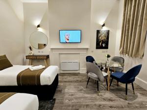 a hotel room with a bed and a table and a tv at Hyde Park Superior Apartments in London