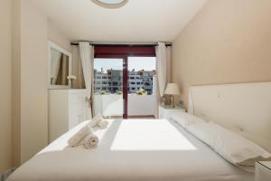 un letto bianco in una stanza con finestra di Apartment, with indoor pool, jacuzzi, sauna and gym, in Benahavis a Estepona