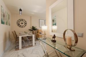 un soggiorno con tavolo in vetro e orologio di Apartment, with indoor pool, jacuzzi, sauna and gym, in Benahavis a Estepona