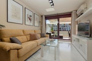 un soggiorno con divano e tavolo in vetro di Apartment, with indoor pool, jacuzzi, sauna and gym, in Benahavis a Estepona