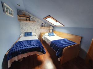 1 dormitorio con 2 camas con sábanas azules y blancas en Casa Marcela, en Gijón