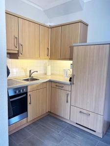eine kleine Küche mit Holzschränken und einem Waschbecken in der Unterkunft Idyllische Ferienwohnung Schmidt 9226 - Burg in Fehmarn