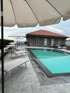 a swimming pool with chairs and an umbrella at Affittacamere villa Antonio in Aci Castello