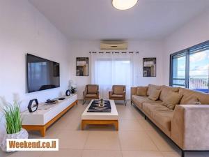 uma sala de estar com um sofá e uma televisão em וילת נופש מגידו em Midrakh ‘Oz