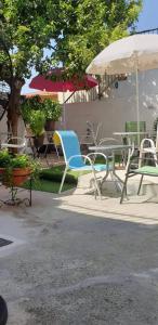 a group of chairs and tables and an umbrella at Marina's Rooms in Larnaca