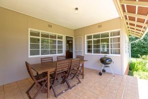 porche cubierto con mesa de madera y sillas en Lowestoffe Country Lodge Rockford en Hogsback